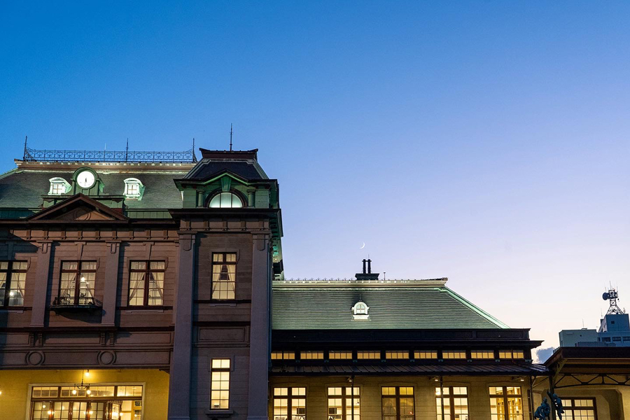 夕暮れの空と三日月を背景にしたJR門司港駅